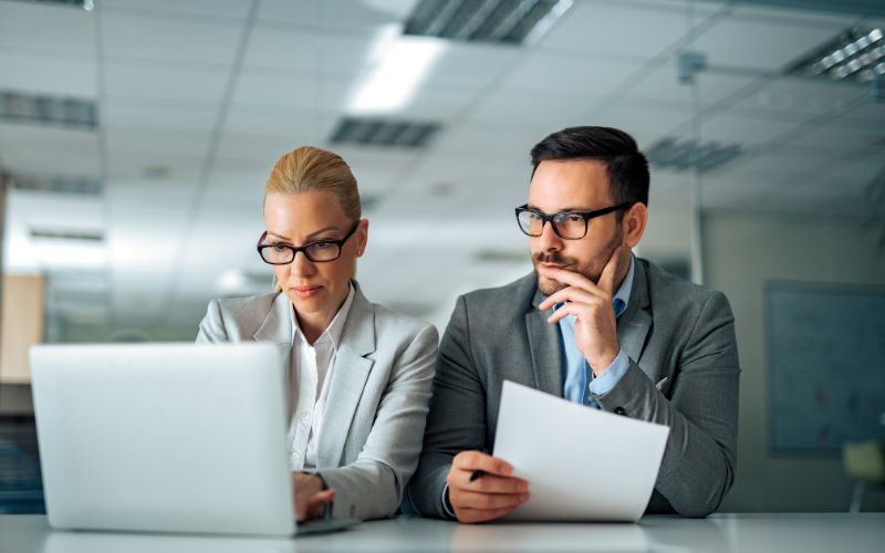 Two tax professionals reviewing the IC-DISC qualification criteria on a laptop, focused on the IC-DISC Export Tax Incentive details.