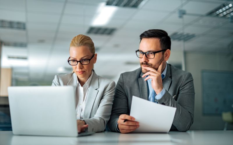 Two export tax expert analyzing a document and requirements on a laptop, engaged in discussions about tax strategies for exporters.